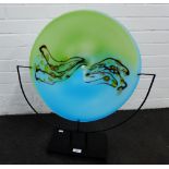 Large Murano style glass circular plate on a black metal stand, 65cm high overall