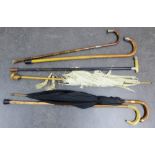 A collection of silver mounted walking canes and sticks, a parasol and an umbrella (6) longest 94cm,