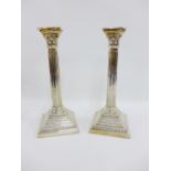 A pair of silver Corinthian column candlesticks on stepped square bases, Birmingham 1957,