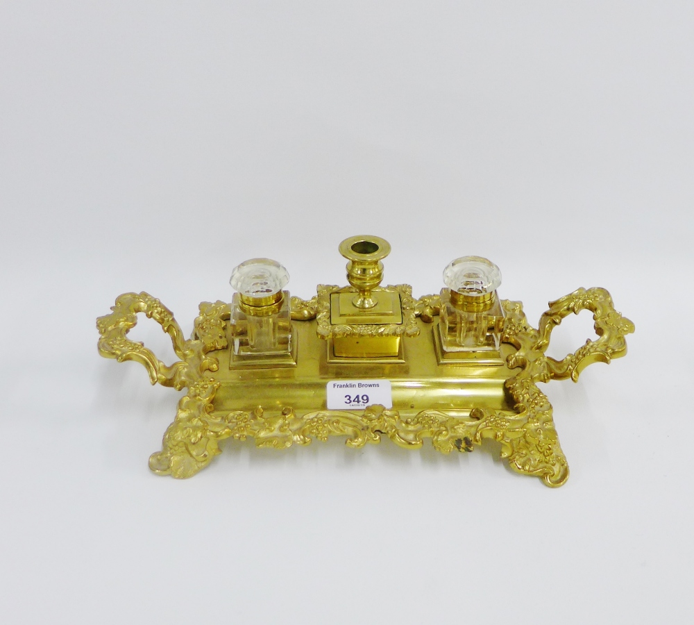 Brass desk ink stand with two glass inkwells and a candlestick to centre, 32cm long