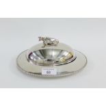 An Epns and glass butter dish and cover, the lid with a cow finial 25cm long