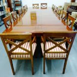 A large cherrywood dining table with extra leaves together with a set of sixteen chairs with crossed