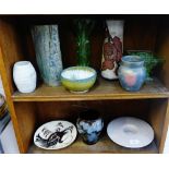 Two shelves of studio pottery together with some Art Deco green glass to include a vase and flower