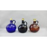 Three colored glass gin flasks with brass mounts to include two include an Amethyst colour, blue and