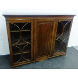 Mahogany bookcase with dentil frieze over central cupboard door flanked by glazed doors with a