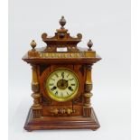 German pine cased mantle clock with urn finials over enamelled chapter ring with Roman numerals on