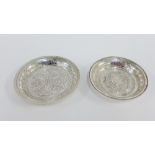 Eastern silver circular trinket dish and a smaller white metal dish, largest 9.5cm diameter (2)