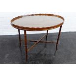 Mahogany table, the oval top with pie crust edge, on faux bamboo supports with cross stretcher, 52 x
