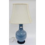 Pale blue glazed ceramic lamp base and shade with an ebonised wooden stand, 35cm high, excluding