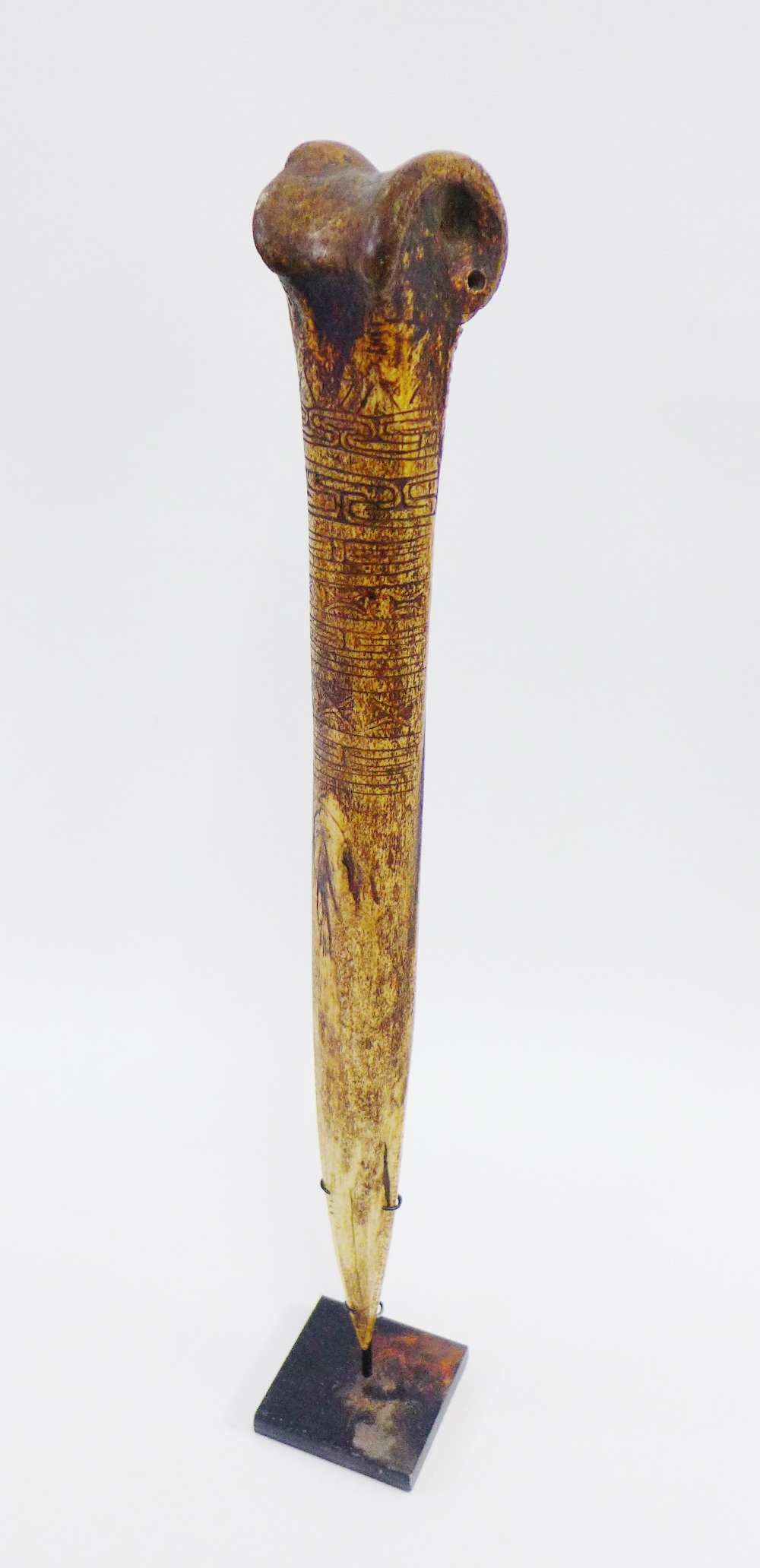 Iatmul, Papa New Guinea Cassowary dagger with carved decoration and serrated edge, on a wooden stand