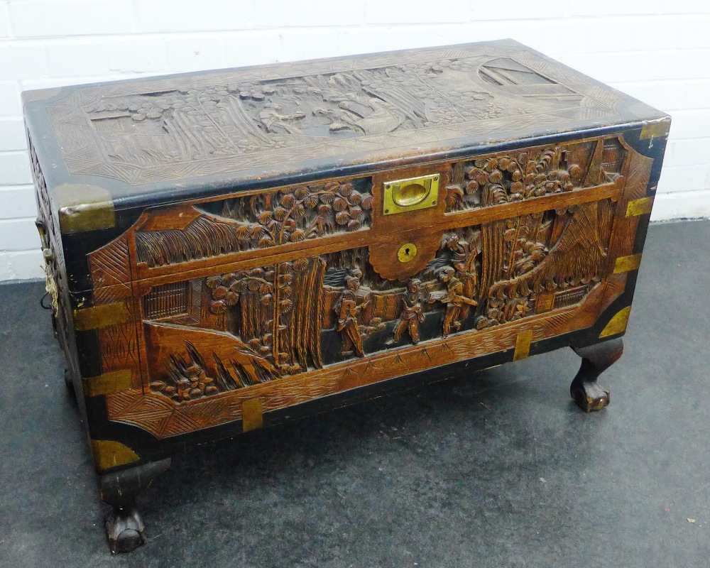 Chinese carved camphor and ebonised wood trunk with brass mounts and handles, on claw and ball feet,