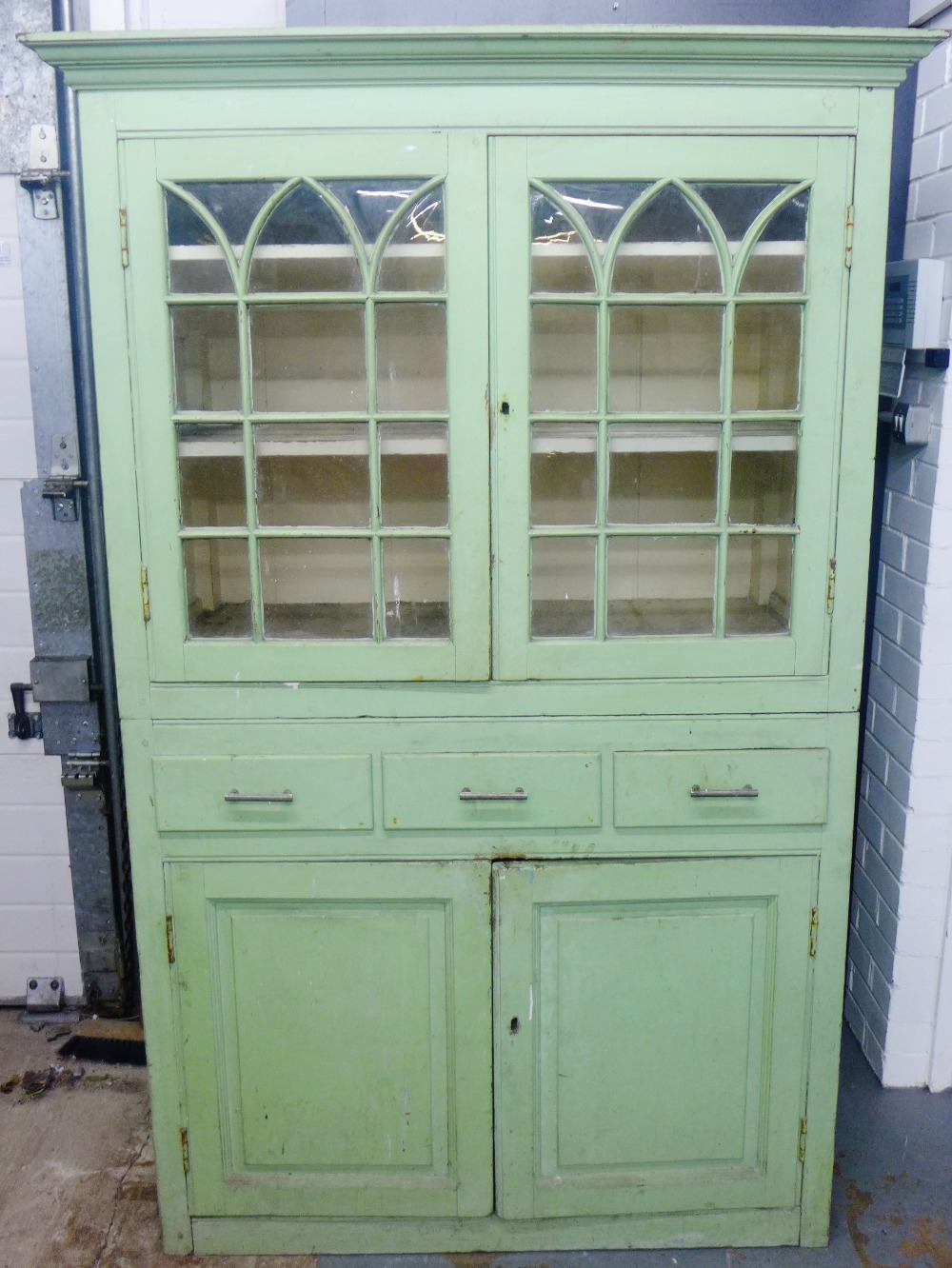 19th century bookcase cabinet painted in institutional green, the top with a pair of lancet glazed