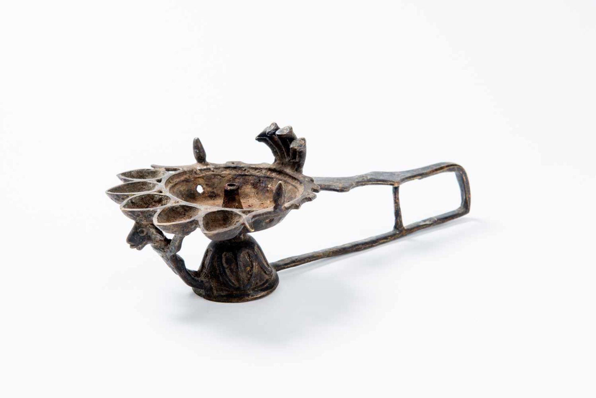 A FIGURAL OIL LAMPBronzeNepal, possibly 19th centuryBell-shaped foot and a long, U-shaped handle,