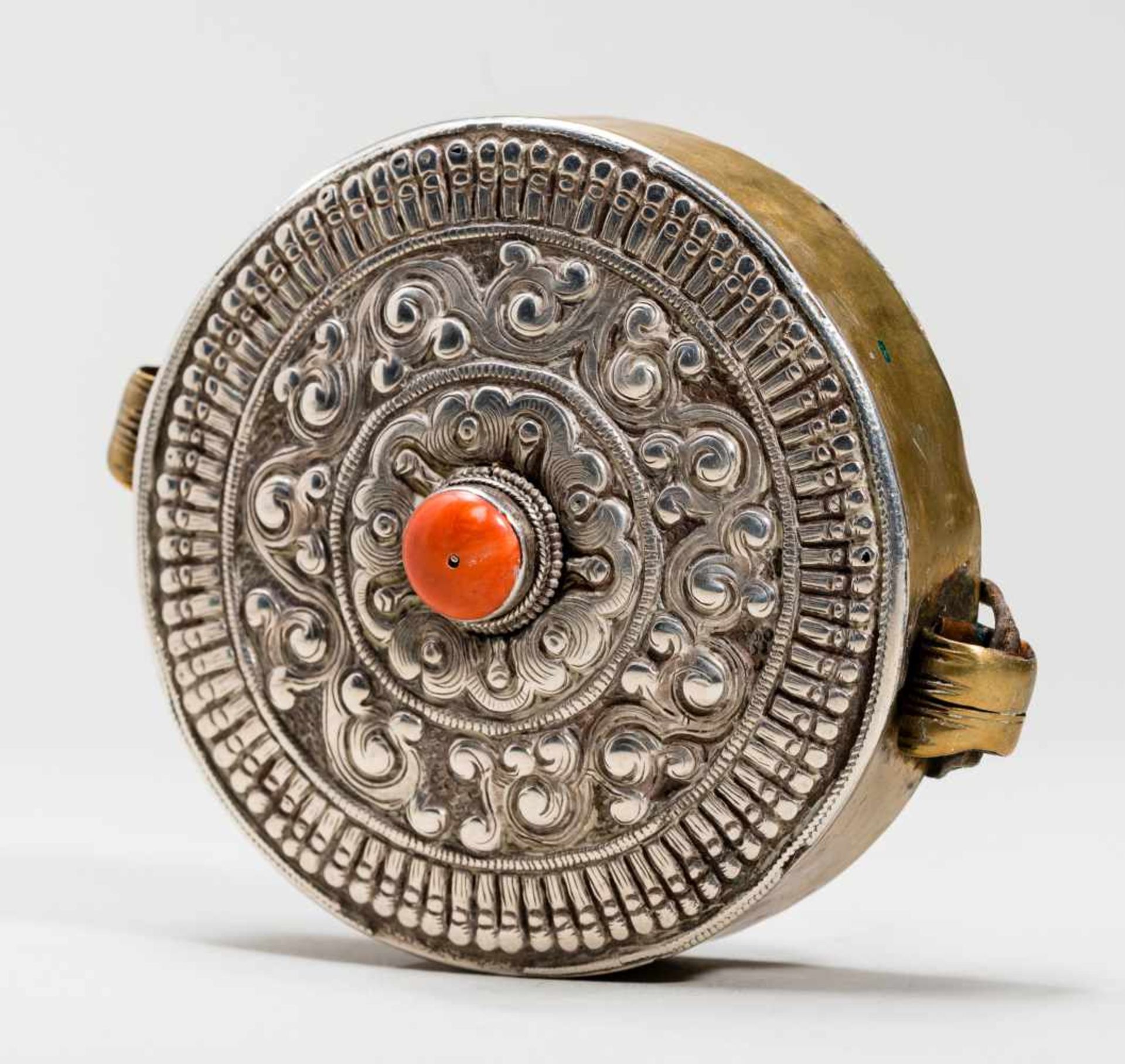 GAU AMULET CONTAINERSilver, brass, coralTibet, late 19th centuryBalanced, circular form, the size of