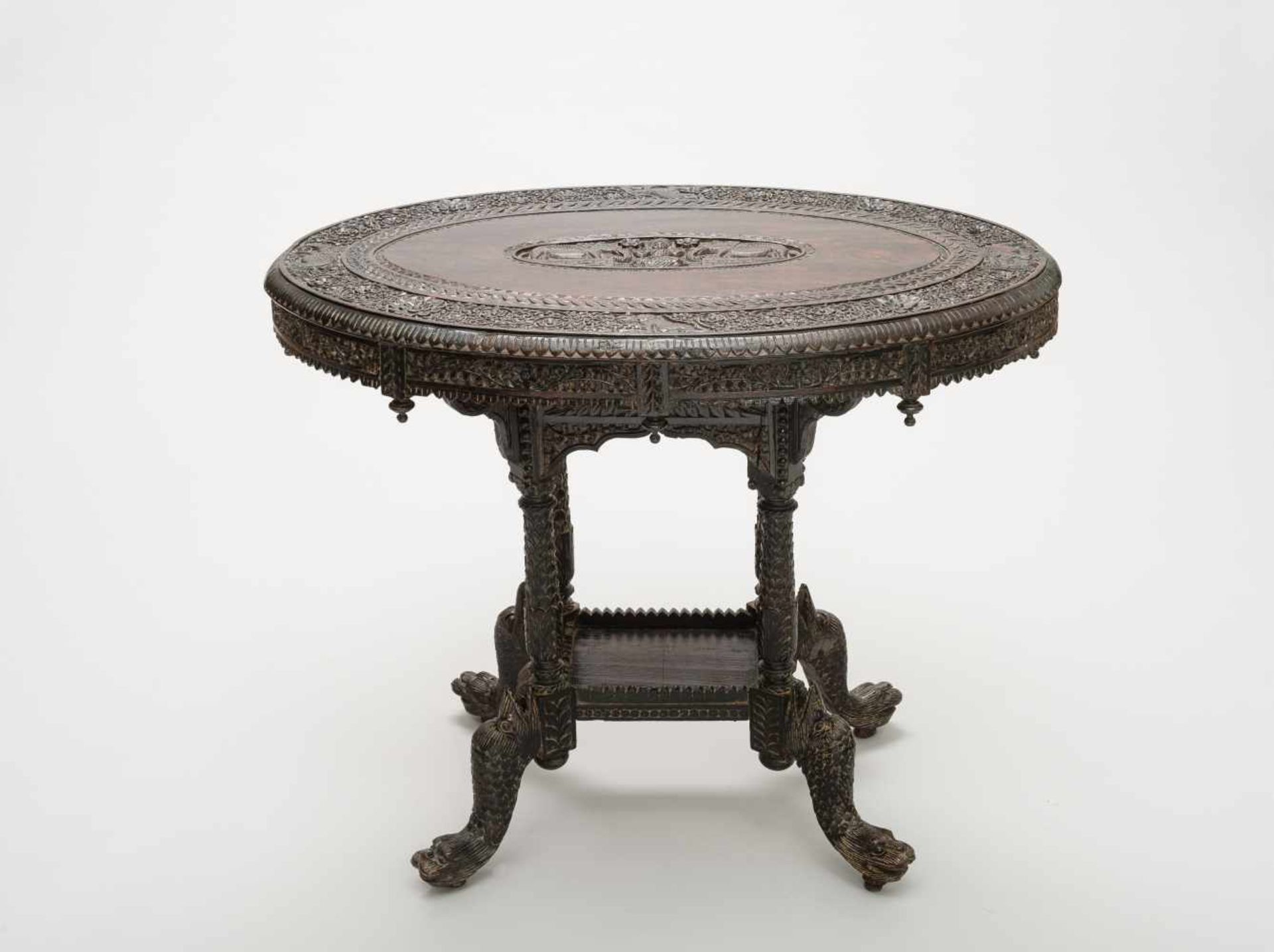 TABLE WITH RICH CARVED DECORRosewood India, 19th cent. Oval round surface with a wide rim