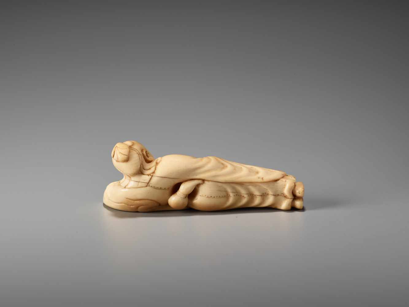 AN IVORY NETSUKE OF A RECLINING CHINESE IMMORTAL WITH A FANUnsigned, ivory netsukeJapan, late 18th - Image 5 of 6