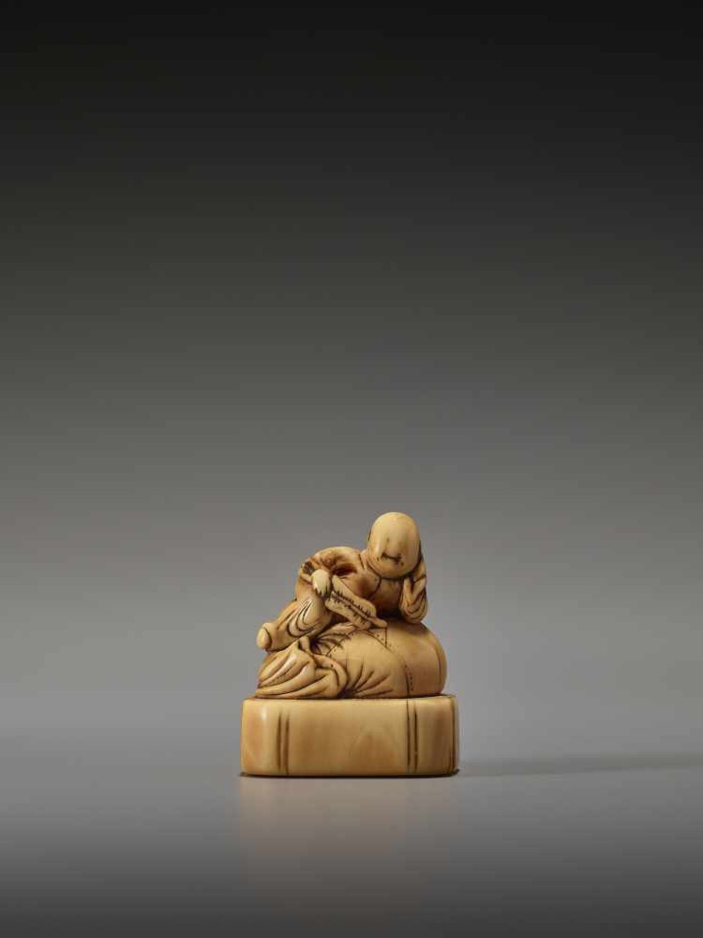 AN EARLY IVORY NETSUKE OF A CHINESE BOY ON HOTEI’S SACKUnsigned, ivory netsukeJapan, 18th century,