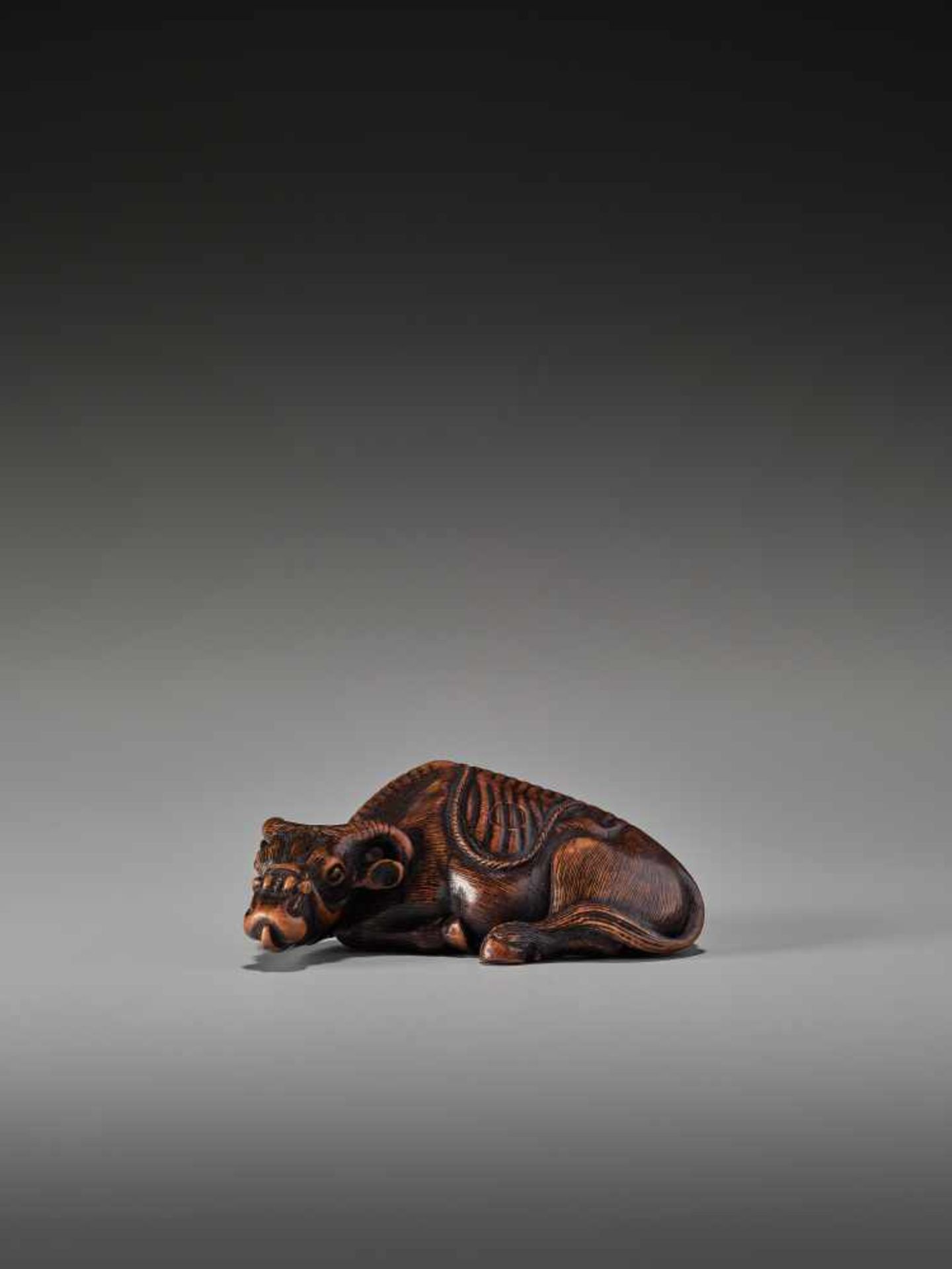 A RARE WOOD NETSUKE OF A RECUMBENT OX SIGNED TOMOTADASigned Tomotada, wood netsukeJapan, 19th