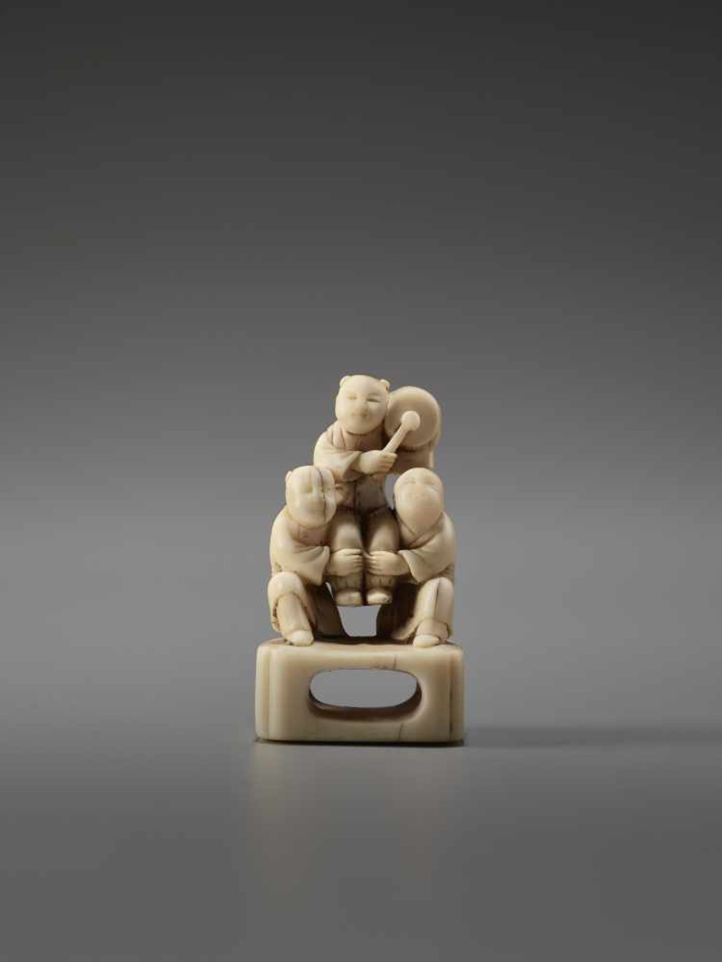 AN IVORY NETSUKE OF THREE CHINESE BOYS AND A DRUMUnsigned, ivory netsukeJapan, late 18th to early