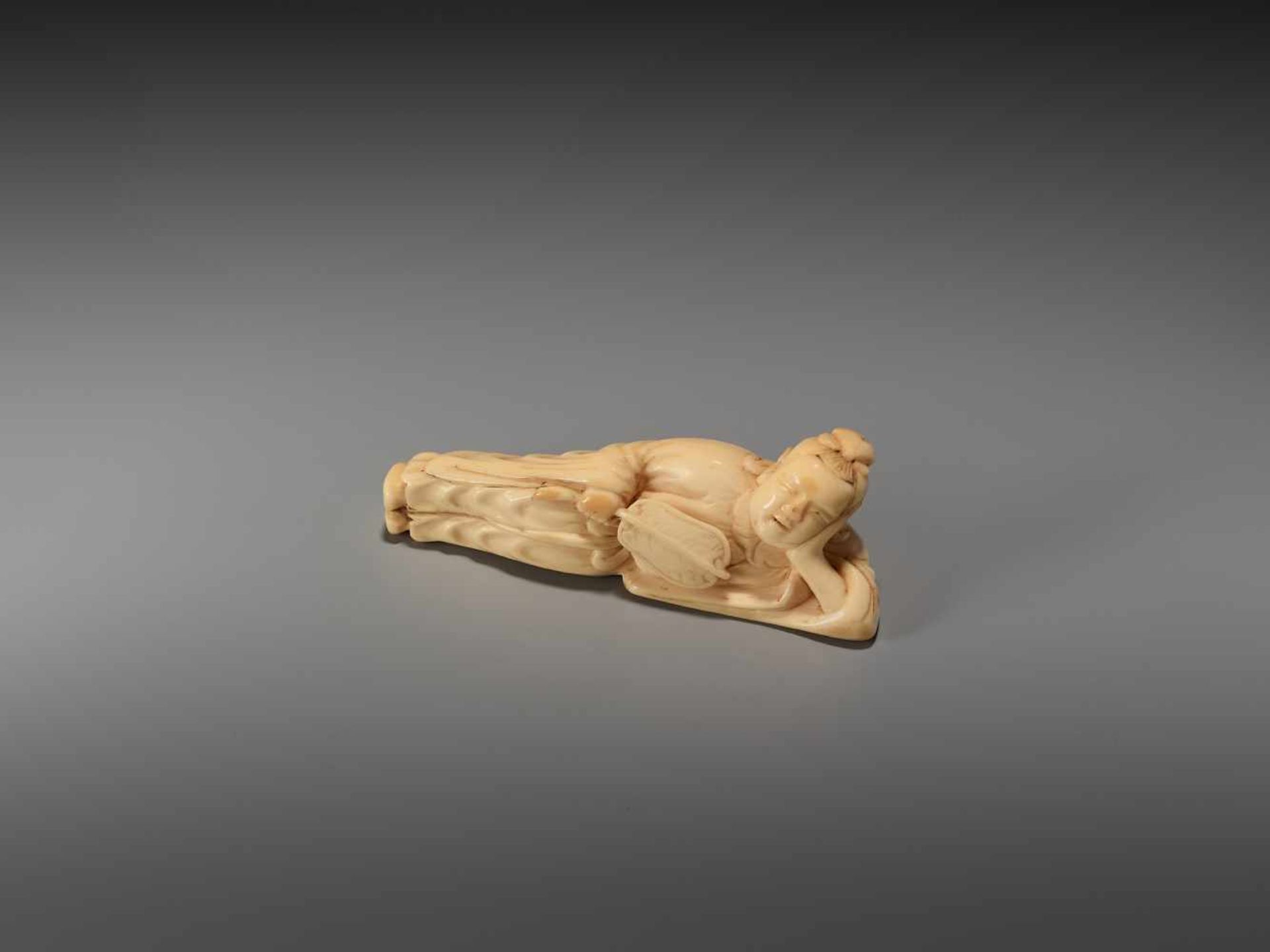 AN IVORY NETSUKE OF A RECLINING CHINESE IMMORTAL WITH A FANUnsigned, ivory netsukeJapan, late 18th