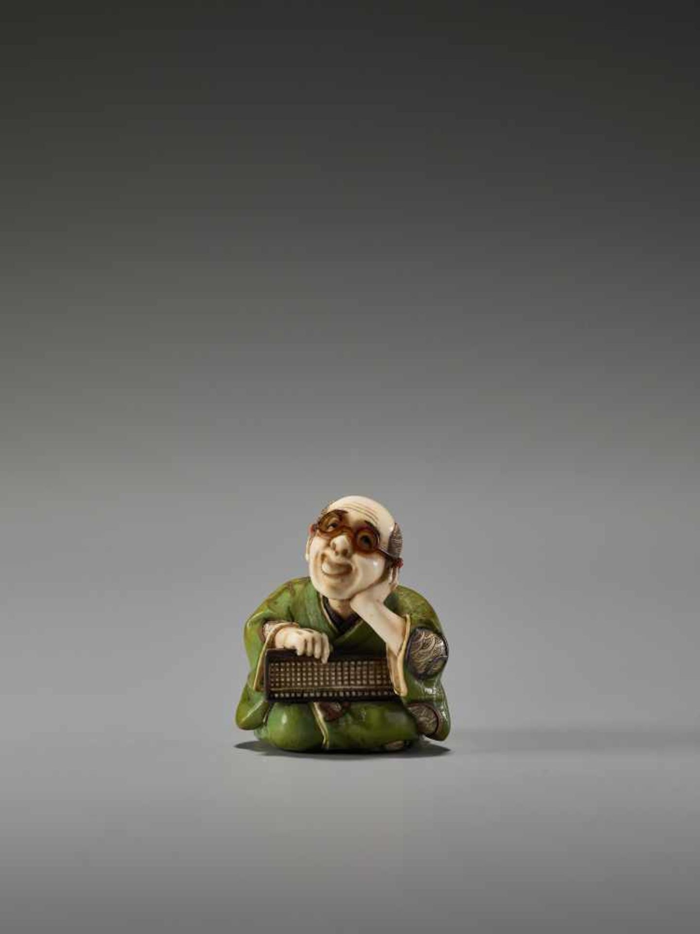 A FINE TOKYO-SCHOOL IVORY NETSUKE OF A MAN WITH GLASSES AND AN ABACUS BY YASUMASABy Yasumasa (