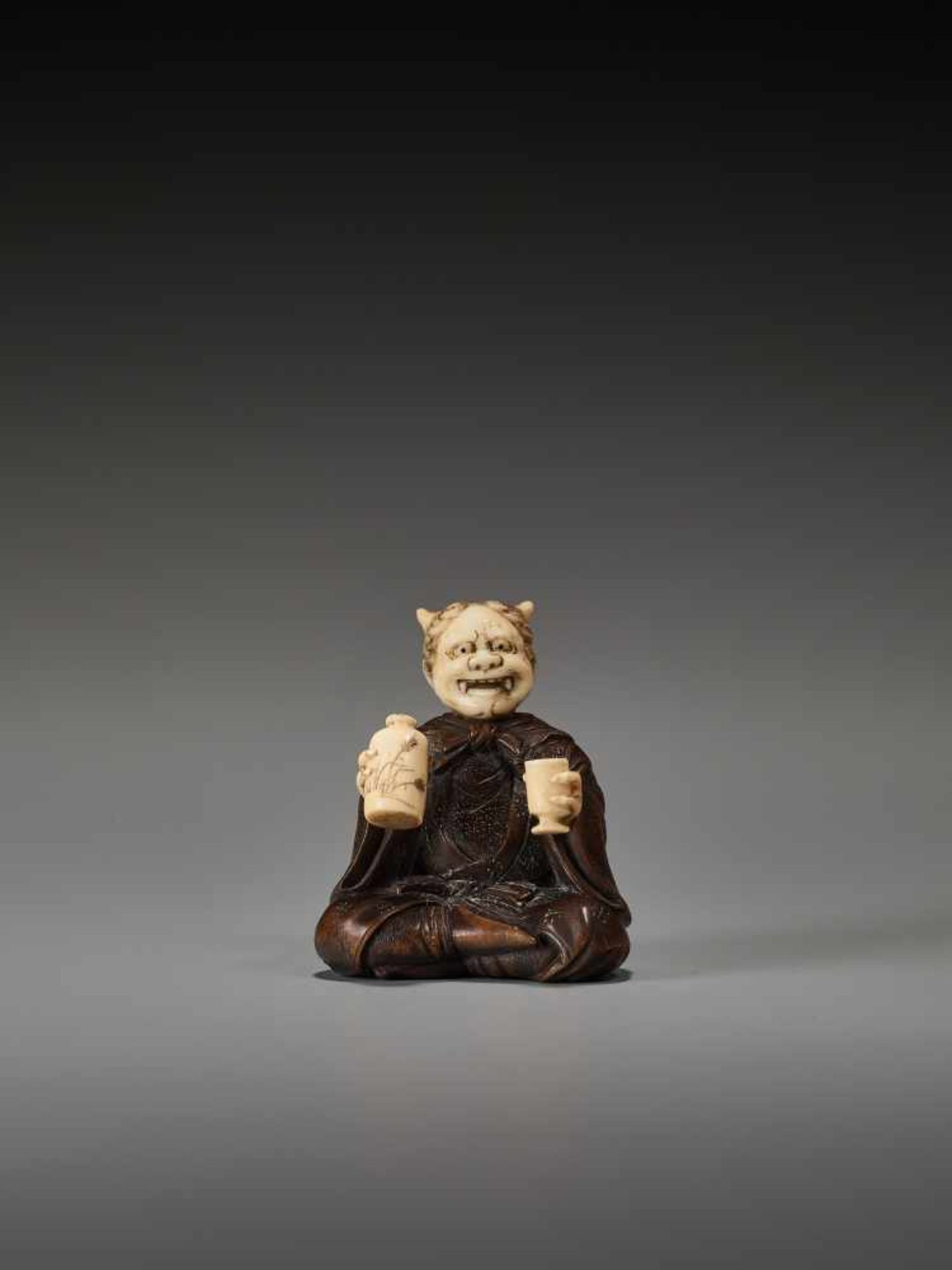 AN UNUSUAL WOOD AND IVORY NETSUKE OF A DRUNKEN ONI BY HOMINBy Homin, wood and ivory netsukeJapan,