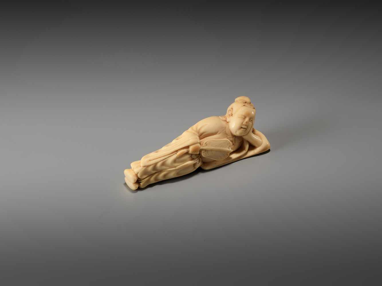 AN IVORY NETSUKE OF A RECLINING CHINESE IMMORTAL WITH A FANUnsigned, ivory netsukeJapan, late 18th - Image 2 of 6
