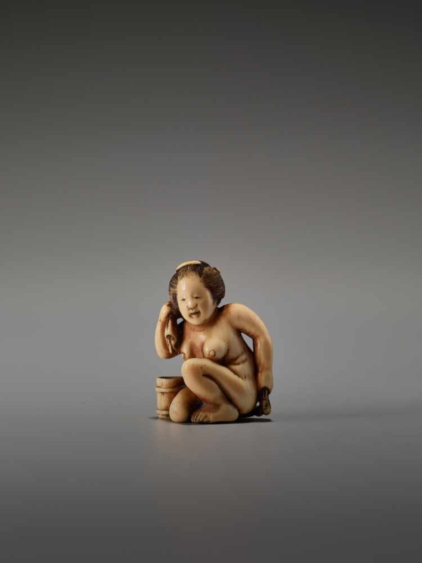 AN IVORY SHUNGA NETSUKE OF A NUDE WOMAN WASHING HERSELF BY THE TOMOCHIKA SCHOOLBy Tomochika, ivory