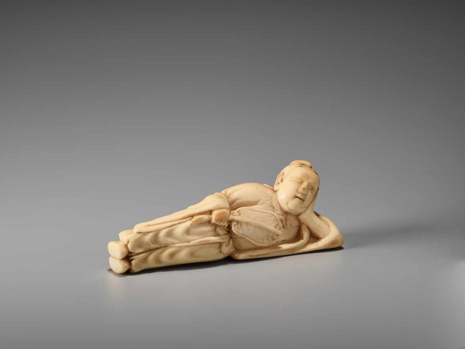 AN IVORY NETSUKE OF A RECLINING CHINESE IMMORTAL WITH A FANUnsigned, ivory netsukeJapan, late 18th - Image 4 of 6