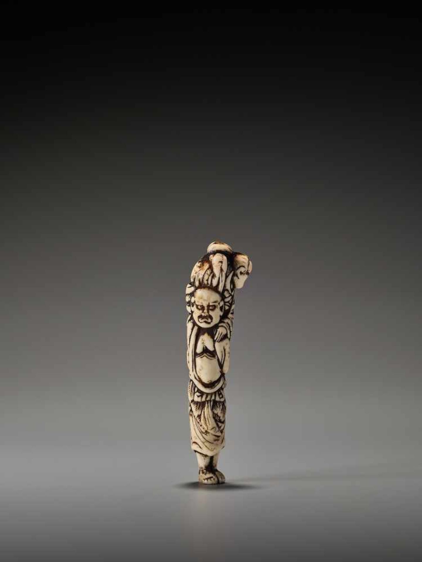 A RARE STAG ANTLER NETSUKE OF IKKAKU SENNIN WITH SENDA BUNINUnsigned, stag antler netsukeJapan, late