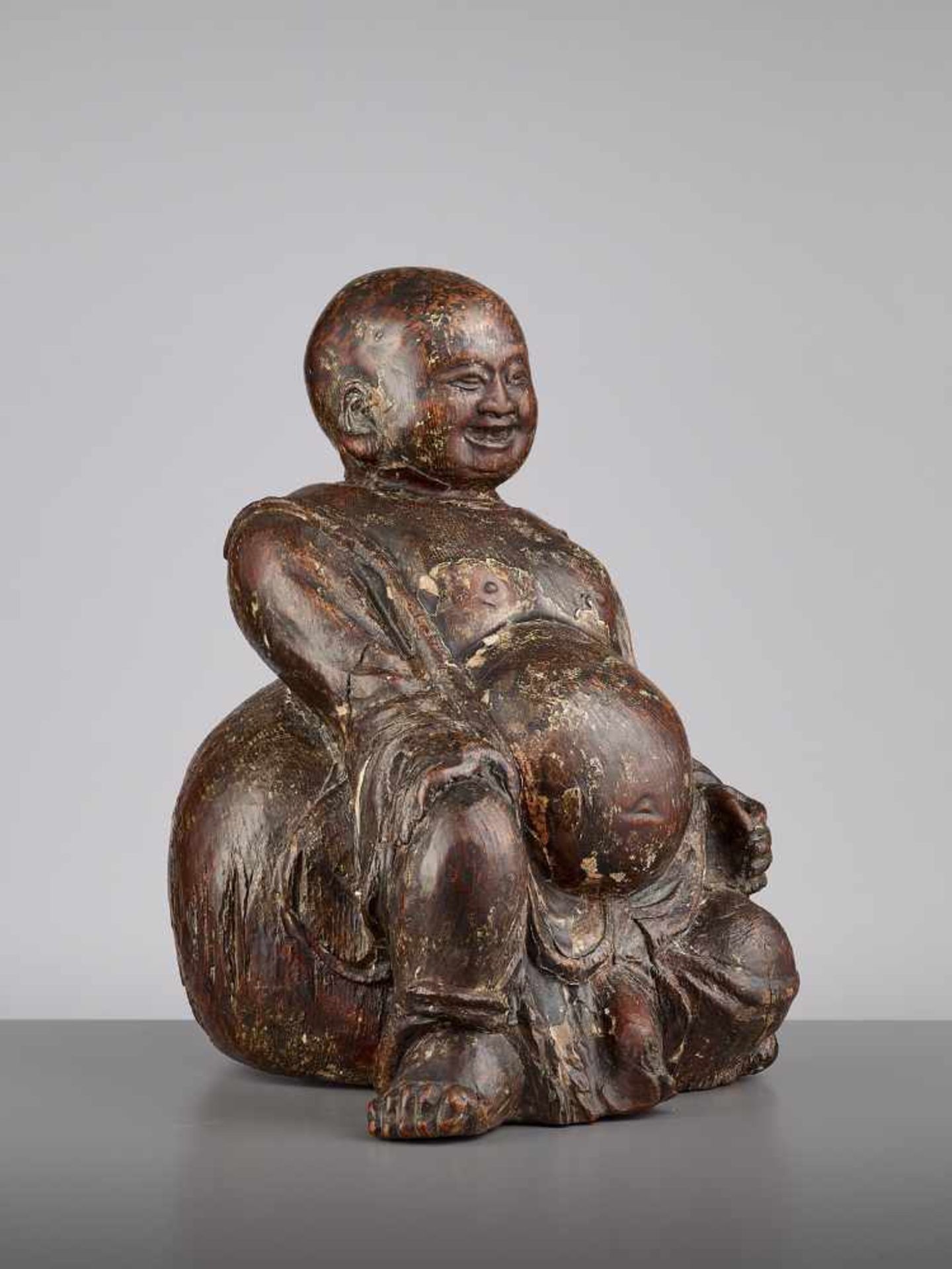 AN EXPRESSIVE WOOD BUDAI, MINGChina, 15th - 16th century. This earthy yet radiant sculpture of Budai