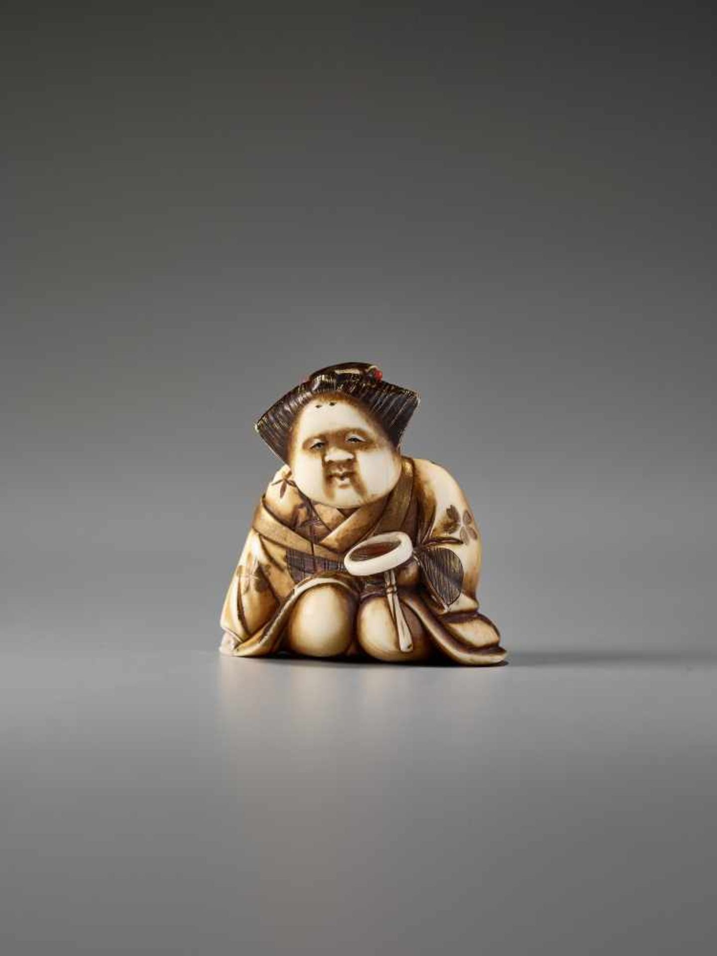 AN IVORY AND LACQUER NETSUKE OF OKAME WITH A SAKE CUP BY KEIMIN By Keimin, ivory netsuke with gold