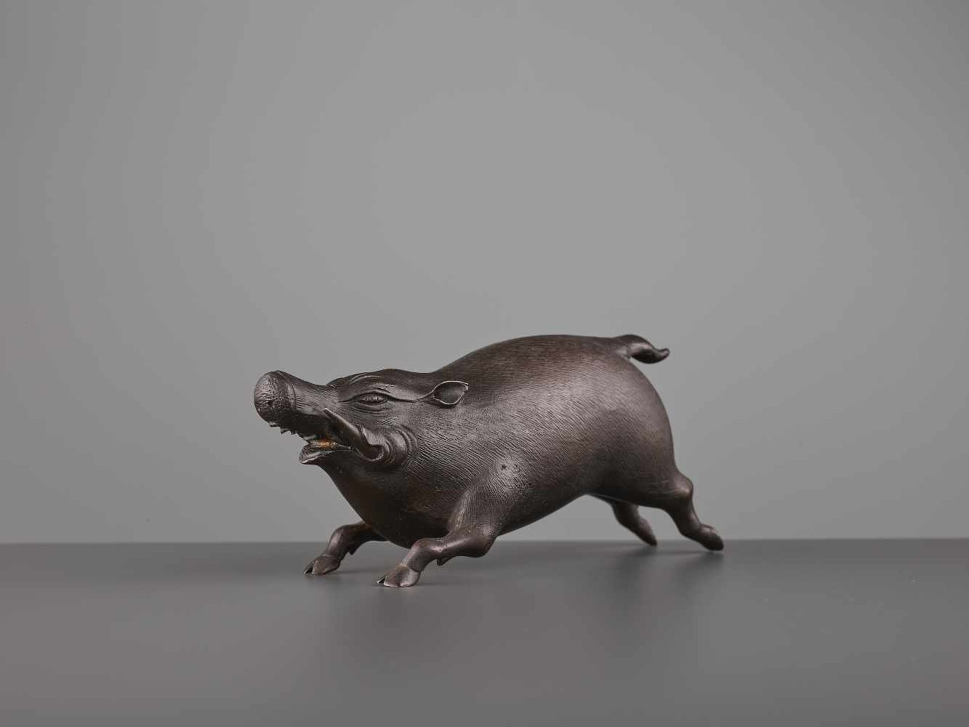 A FINE BRONZE OF A RUNNING BOAR Japan, Meiji period (1868-1912). The bronze figure with dark