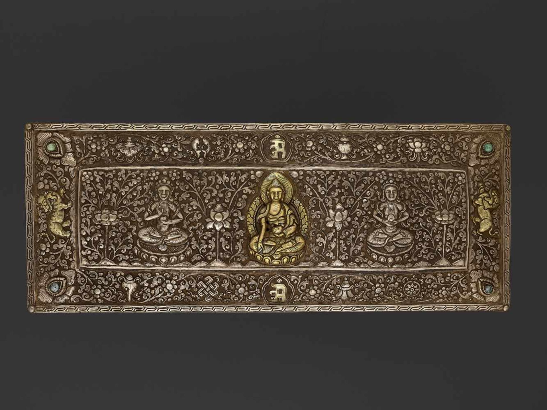 A SILVER REPOUSSÉ MANUSCRIPT COVER Tibet, late 18th – earlier 19th century. A gilt Buddha Shakyamuni