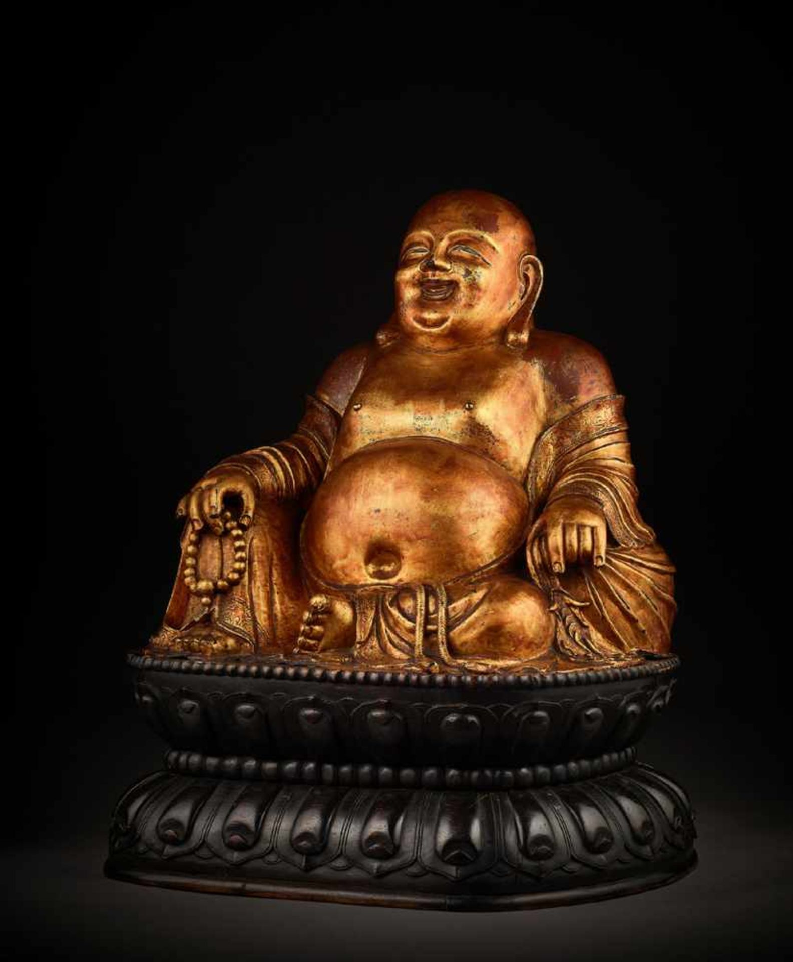 A LARGE GILT BRONZE FIGURE OF BUDAI China, 1368-1644. The smiling, corpulent figure is shown