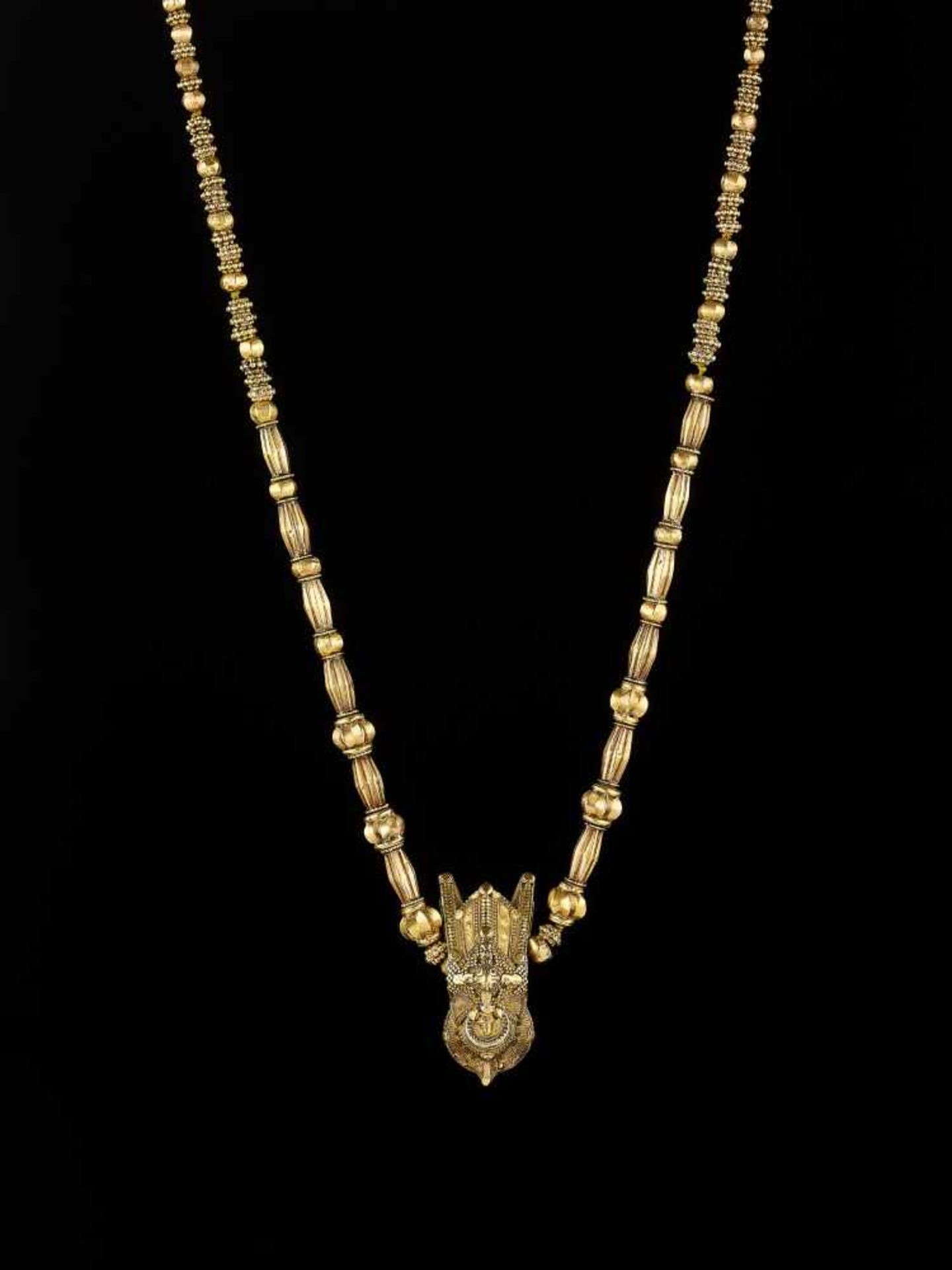 A TODA ‘BULLS HEAD’ GOLD NECKLACE Southern India, mid-19th to early 20th century. The central