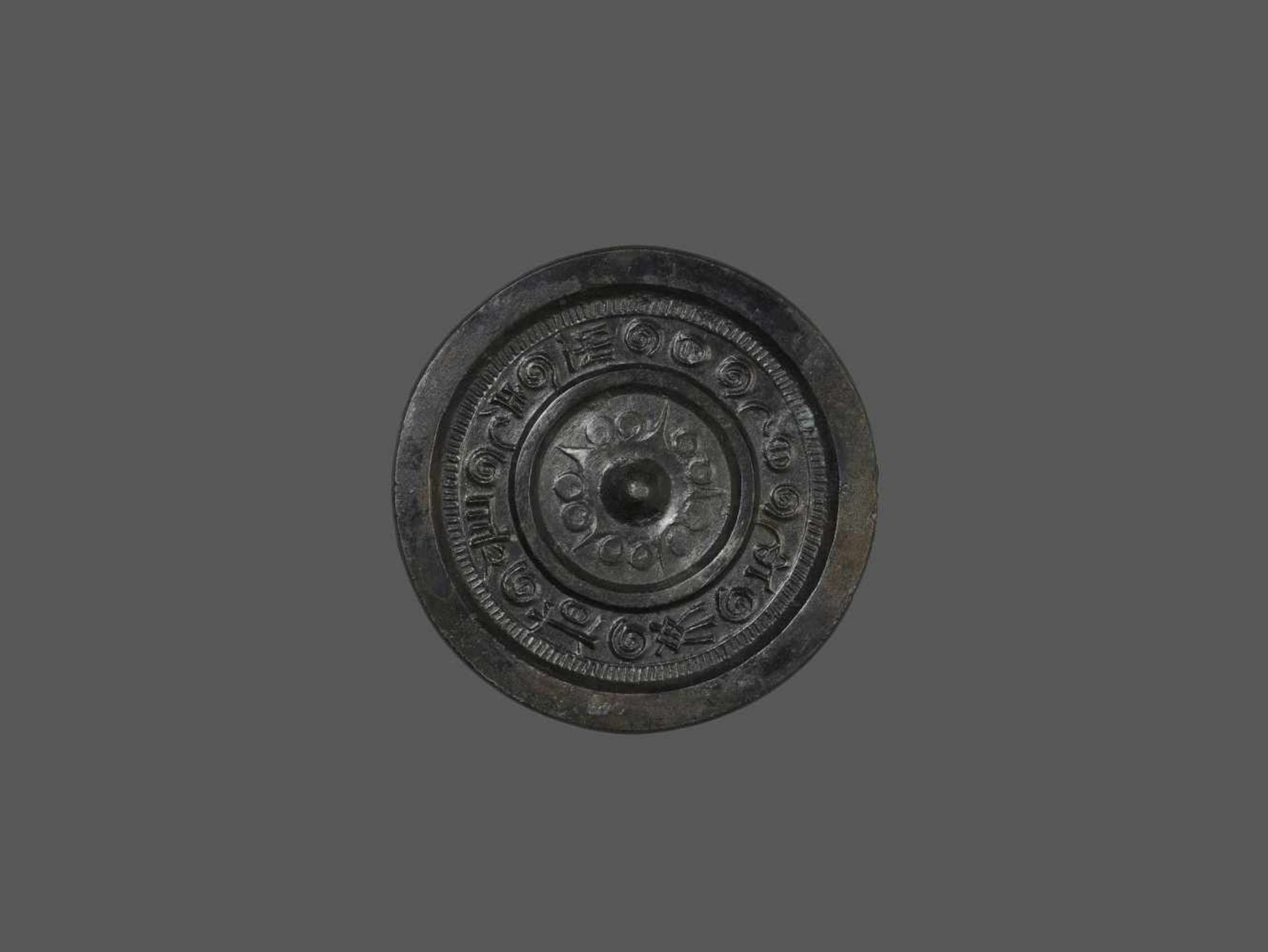 AN INSCRIBED BRONZE MIRROR China, 3rd – 4th century. The suspension knob surrounded by two