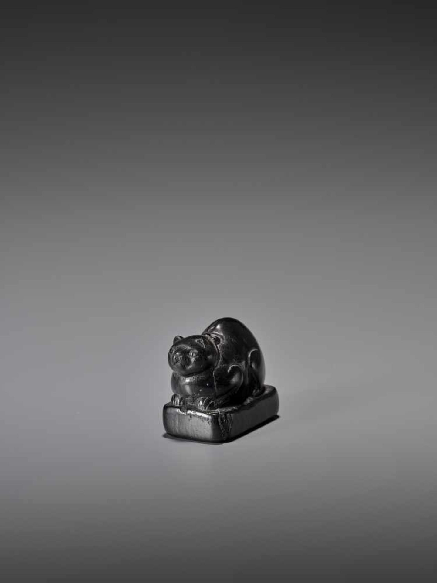 AN EARLY EBONY WOOD NETSUKE OF A WELL-FED CAT ON A BASE UnsignedJapan, early 18th century, Edo