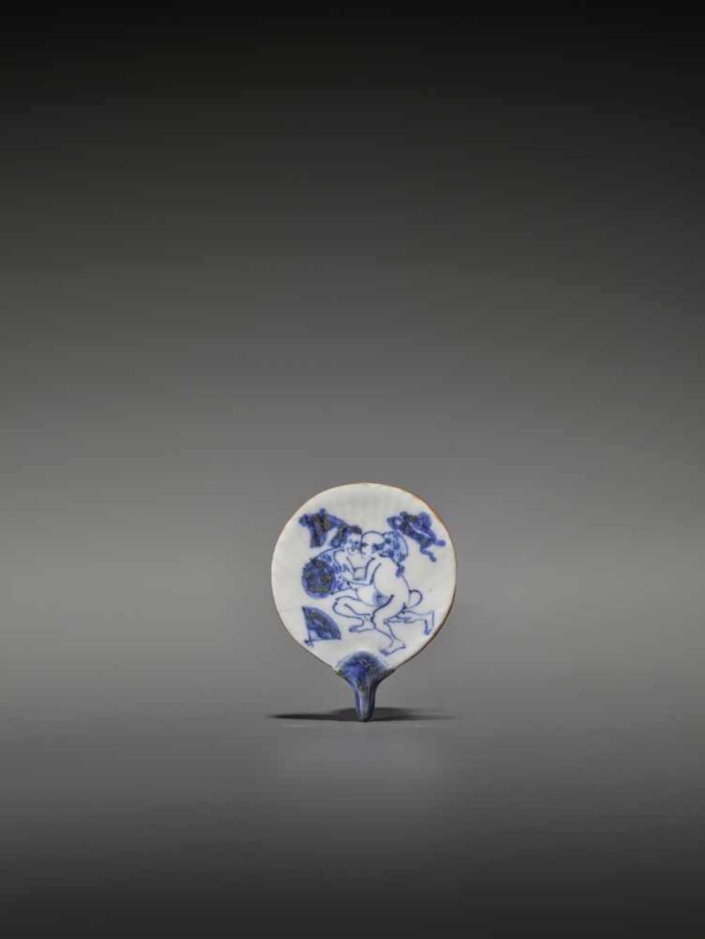 AN UNUSUAL AND RARE FAN-SHAPED BLUE AND WHITE PORCELAIN SHUNGA NETSUKE UnsignedJapan, 19th