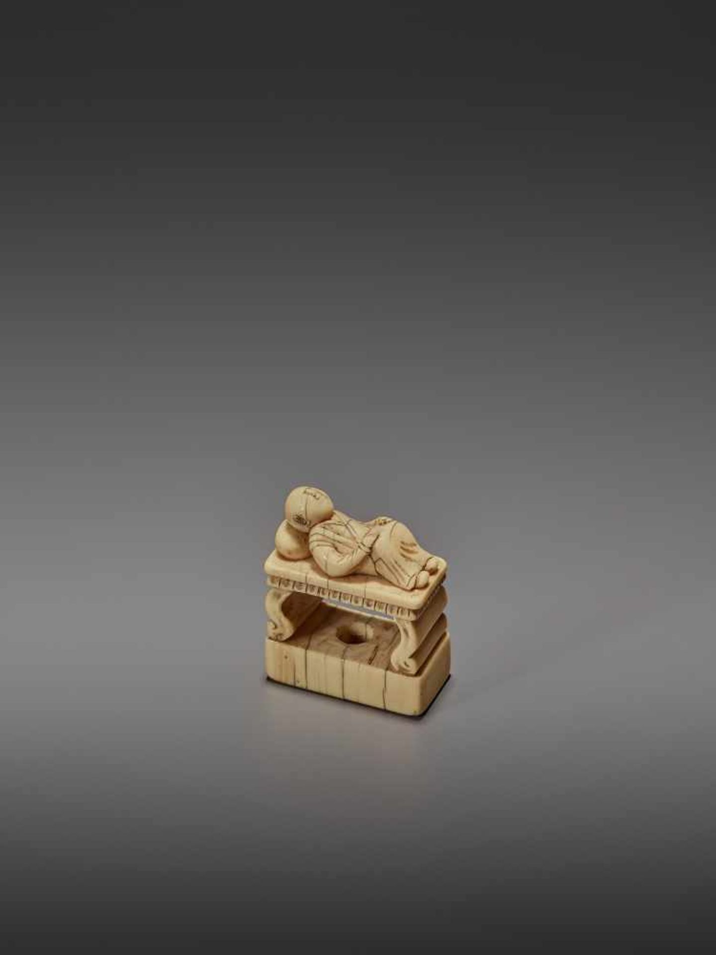 AN EARLY IVORY NETSUKE OF A CHINESE MAN SLEEPING ON AN OPIUM BED UnsignedJapan, early 18th