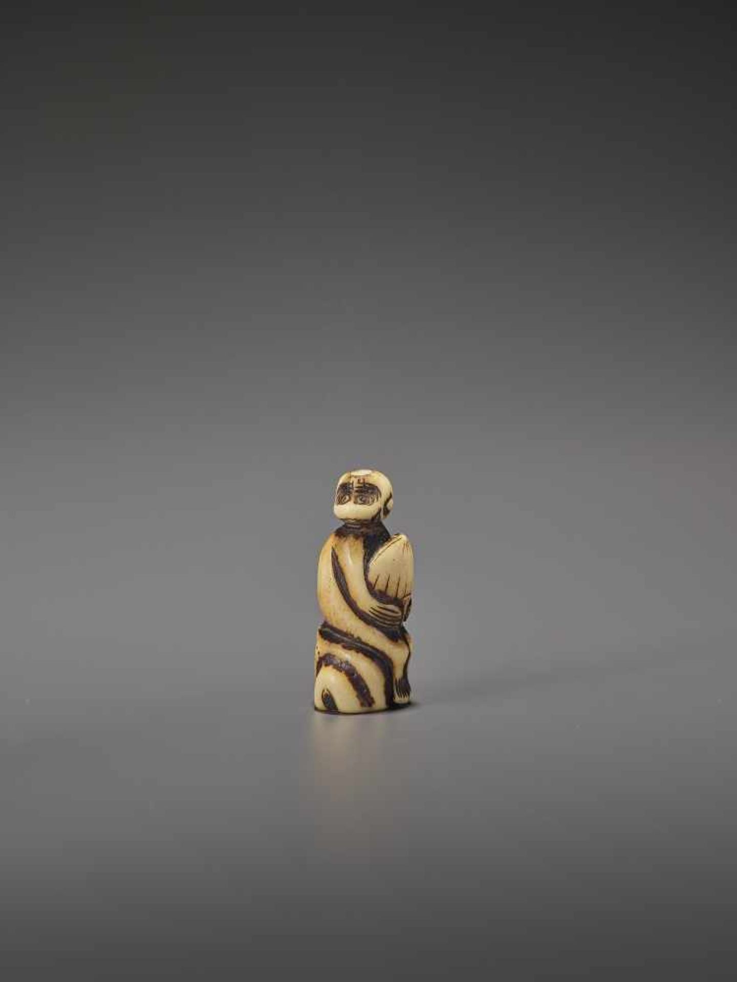 A STAG ANTLER NETSUKE OF A MONKEY WITH CHESTNUT UnsignedJapan, 18th century, Edo period (1615-1868)
