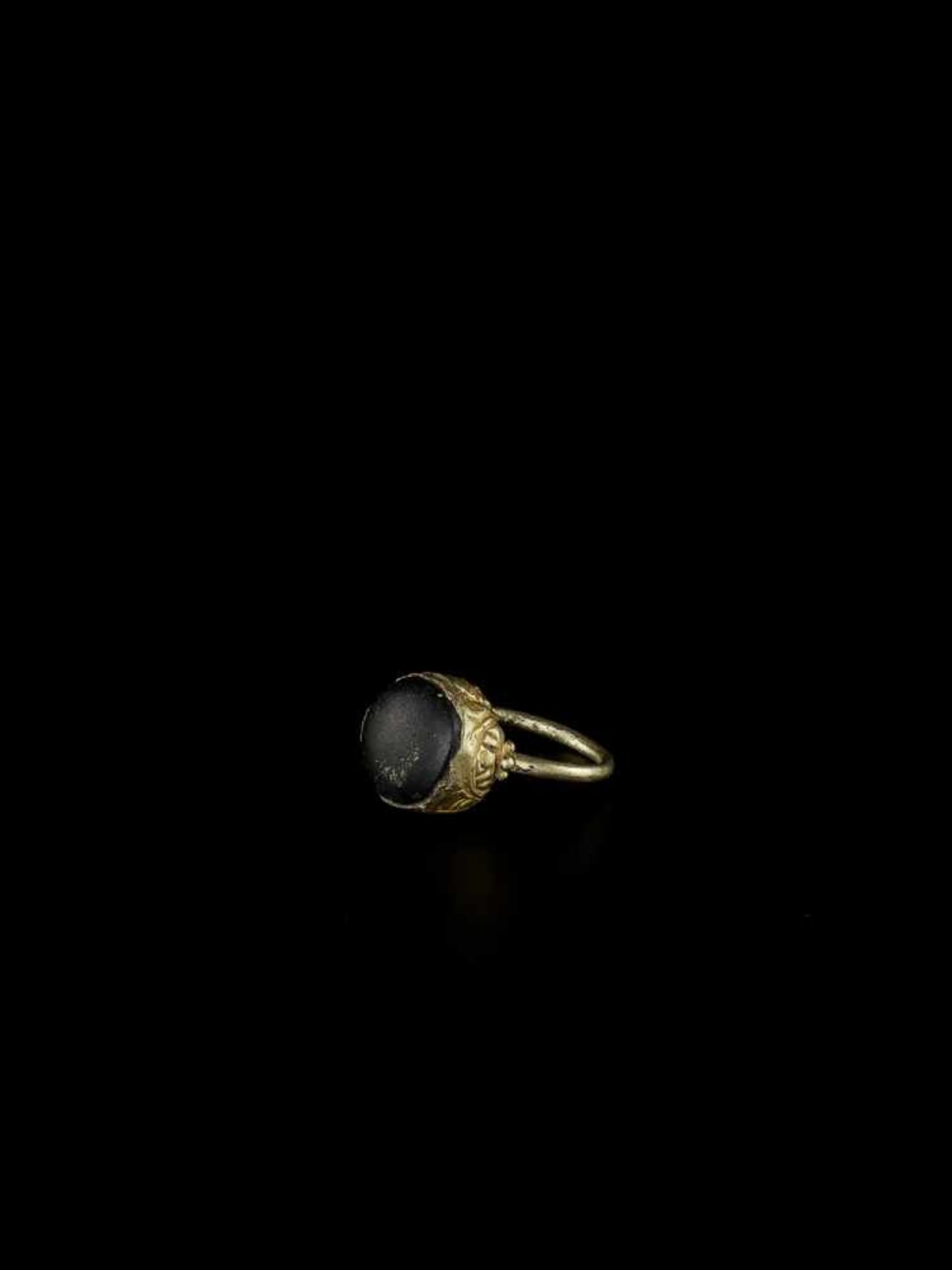 A CHAM GOLD RING WITH A BLACK STONE Champa, c. 12th century. The gold ring topped with a round