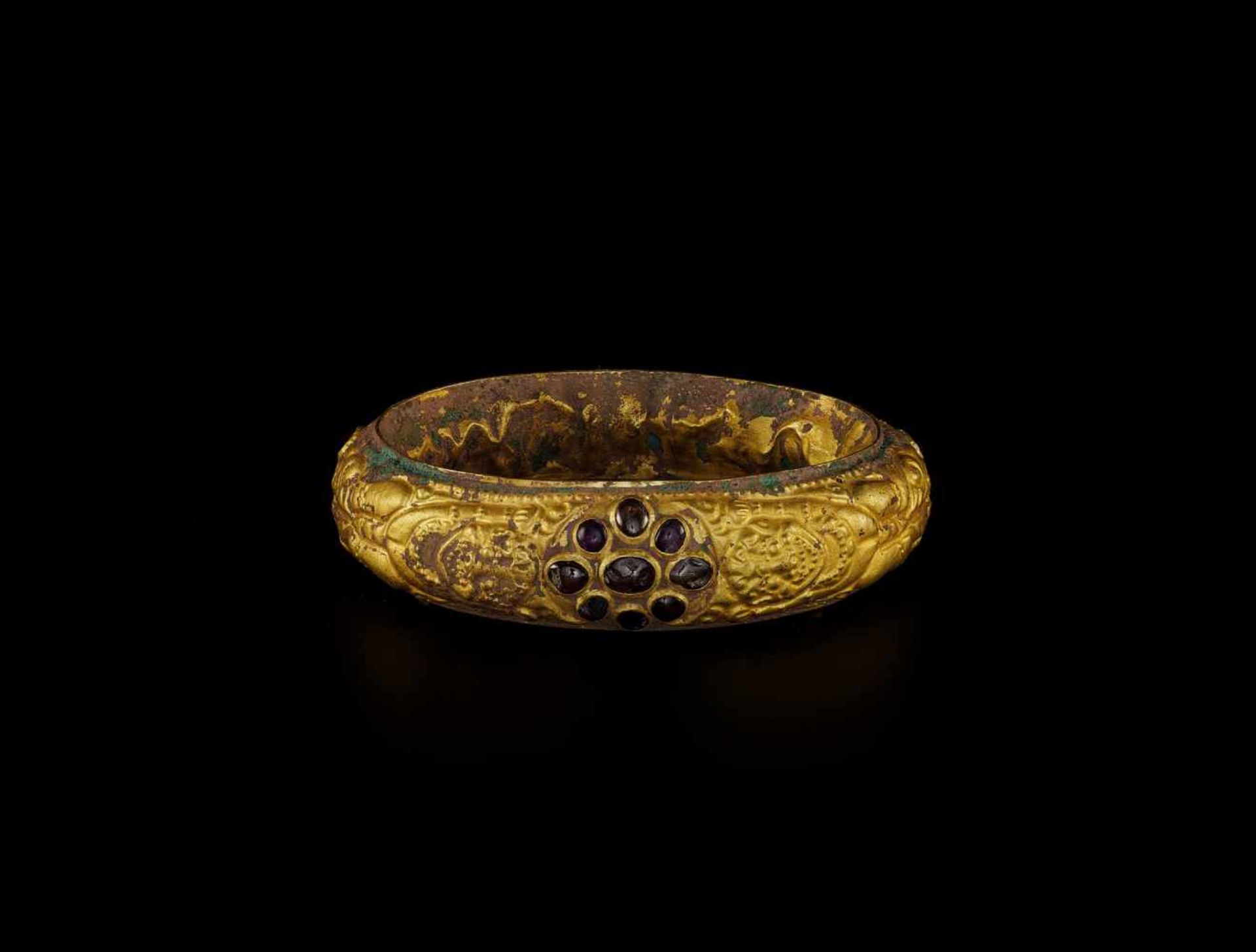A CHAM REPOUSSÉ GOLD BRACELET WITH A GEMSTONE FLOWER AND GUARDIAN LIONS Champa, classical period,