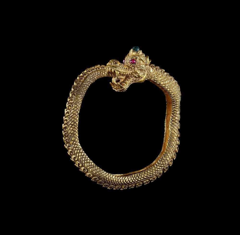 A GOLD DRAGON BANGLE WITH RUBY EYES AND A GREEN GEMSTONE Malaysia, c. 18th – 19th century. An