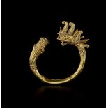A MANDALAY GOLD BANGLE WITH A DRAGON HEAD AND LOTUS FLOWER Myanmar, 20th century. The lower end of