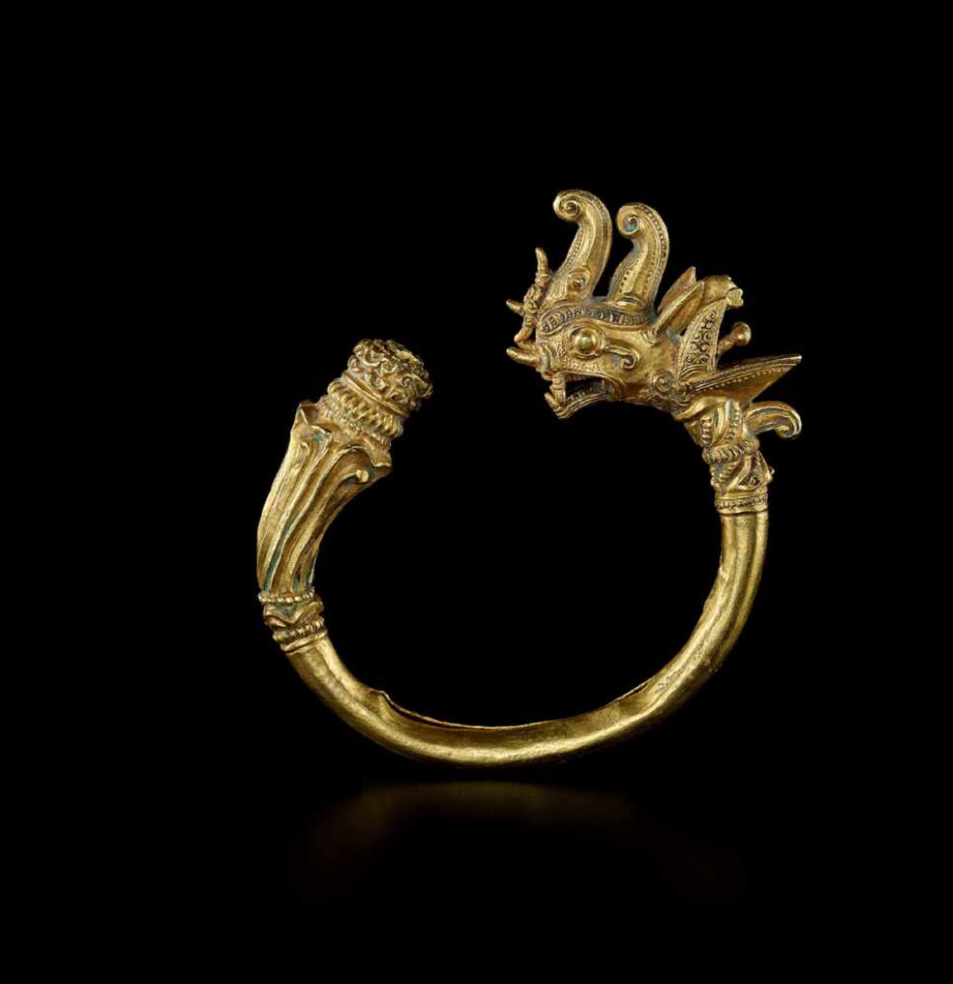 A MANDALAY GOLD BANGLE WITH A DRAGON HEAD AND LOTUS FLOWER Myanmar, 20th century. The lower end of