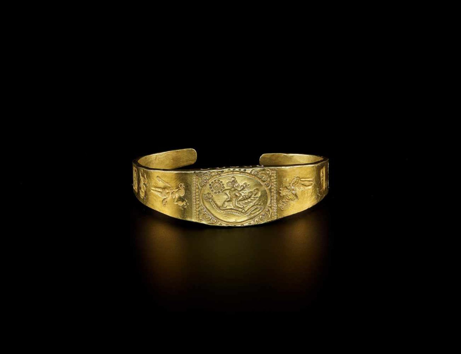 A MASSIVE OPEN GOLD BANGLE WITH GARUDA SUBDUING A NAGA Java, Indonesia, 20th century. The massive