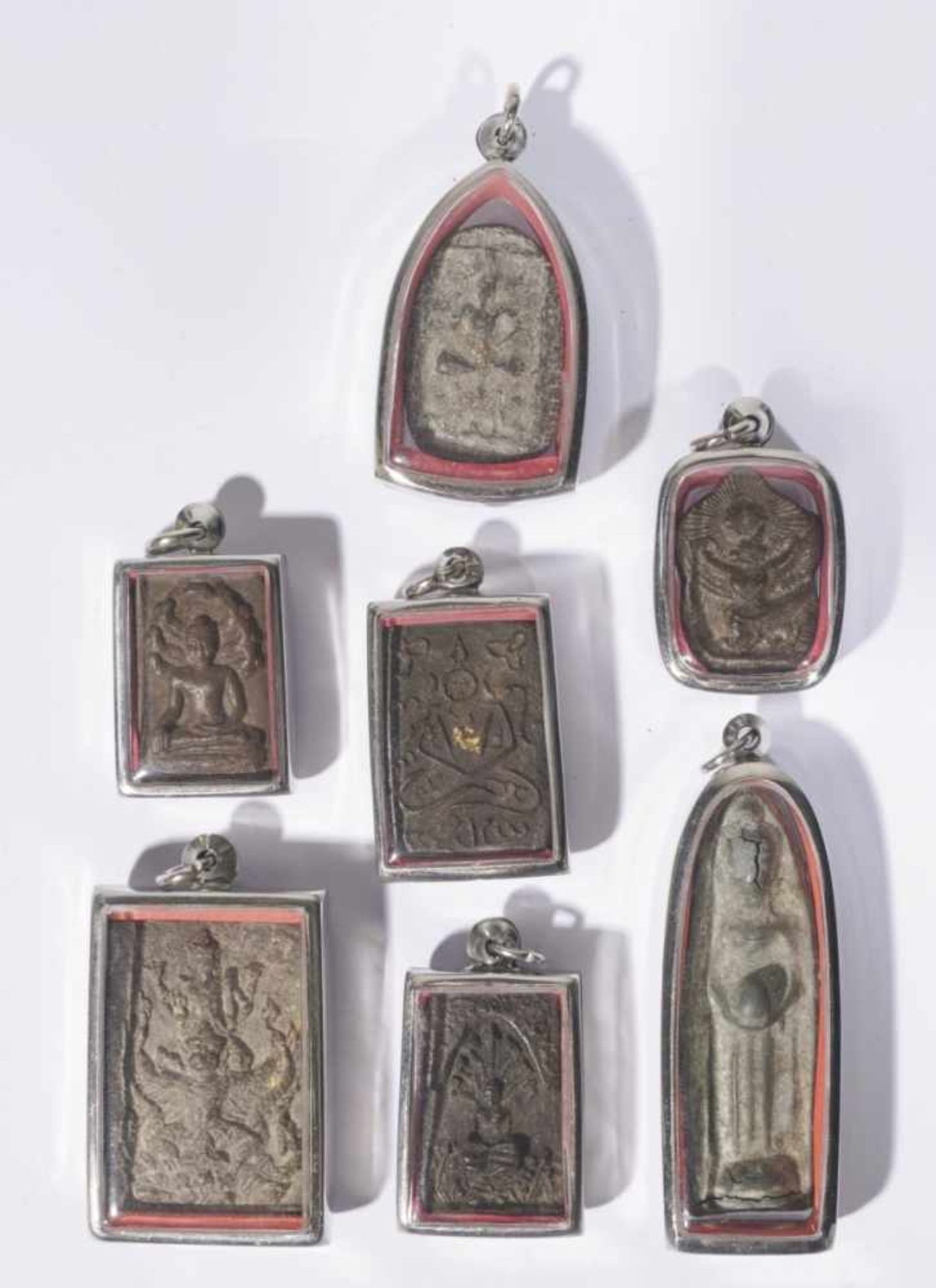 Seven antique buddhist amulet pendants, each set in a modern pendant under glass, from 3