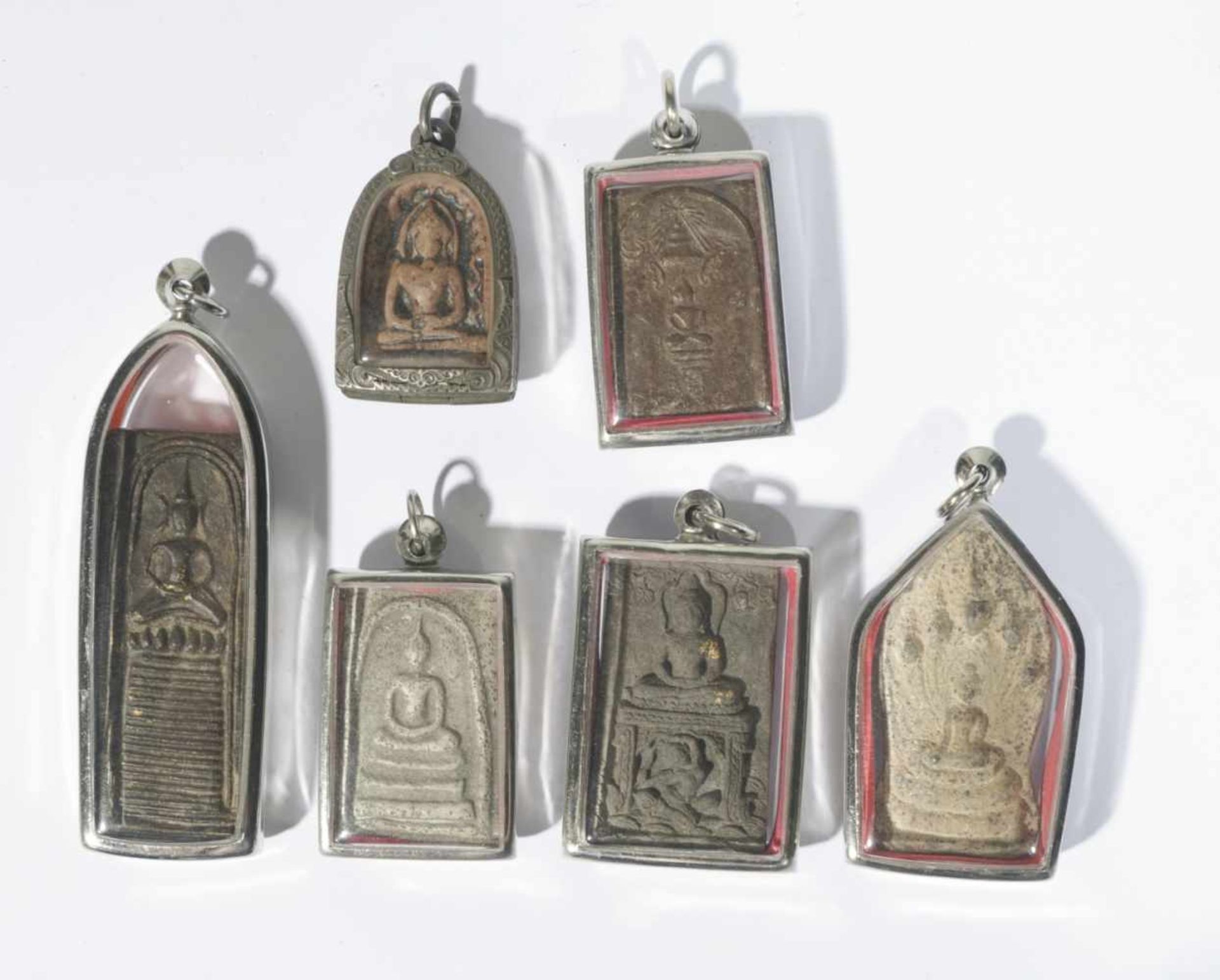 Six antique buddhist amulet pendants, each set in a modern pendant under glass, from 3.5