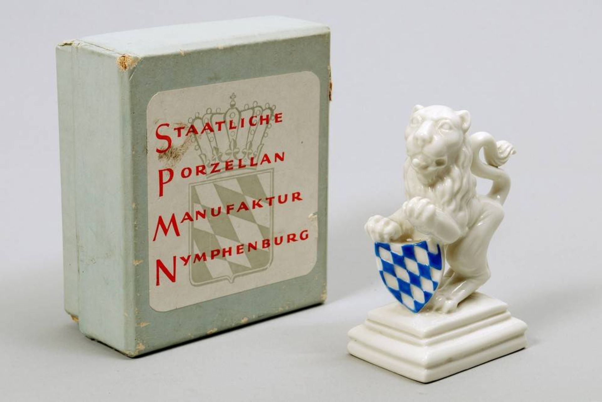 Lion Nymphenburg, 2nd half 20th C., porcelain, original box, marked, H: 9,5cm, tail restored, some